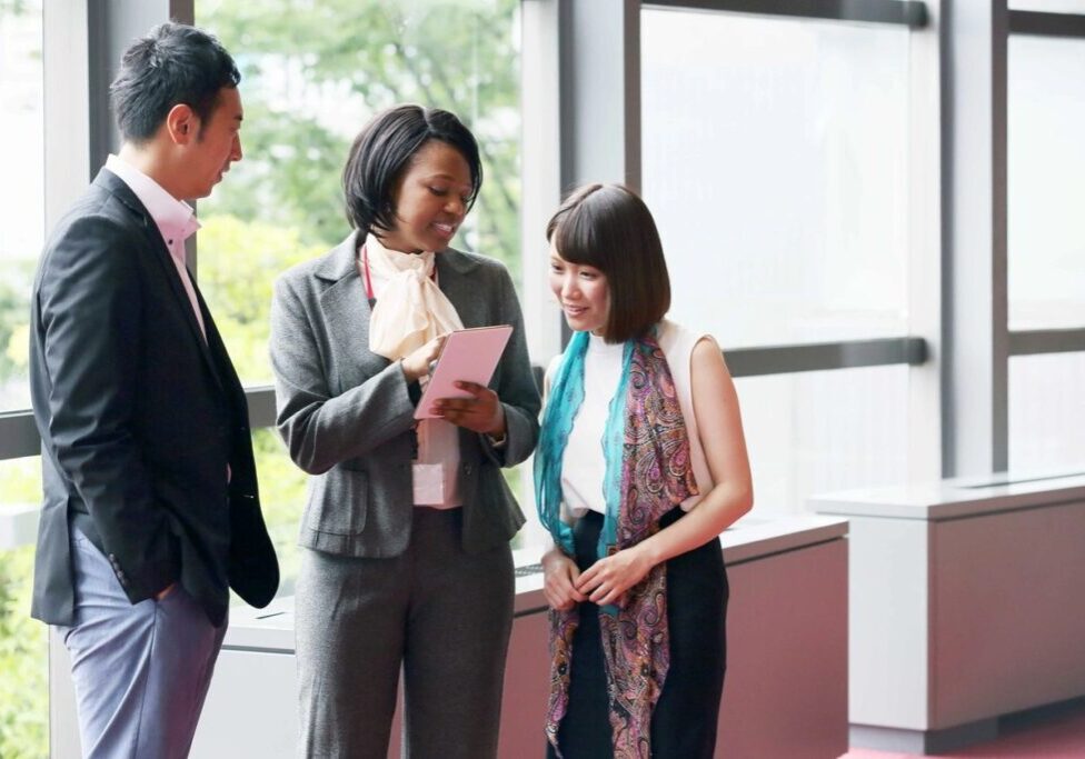 Three people standing in a room talking to each other.